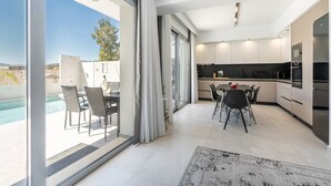 Une cuisine moderne avec un coin repas, de grandes fenêtres et une vue sur la piscine.