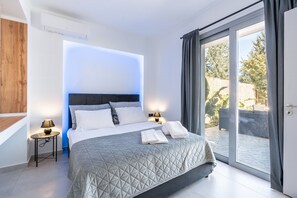 A modern bedroom with a large bed, a bedside table with a lamp, and a sliding glass door to the outside. - Country House 'Mb Luxury' with Mountain View, Wi-Fi and Air Conditioning (Rhodes)