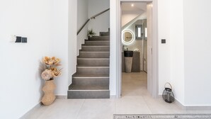 Un intérieur moderne agrémenté d’un escalier, d’un vase décoratif et d’une lanterne.