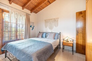 A bedroom with a bed, wooden ceiling, curtains, a bedside table with a lamp, and a wall hanging. - Holiday Home 'Mb Luxury House' with Sea View, Wi-Fi and Air Conditioning (Te??????)