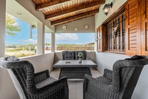 A covered patio with wicker furniture, a table with a potted plant, and a view of the landscape. - Holiday Home 'Mb Luxury House' with Sea View, Wi-Fi and Air Conditioning (Te??????)