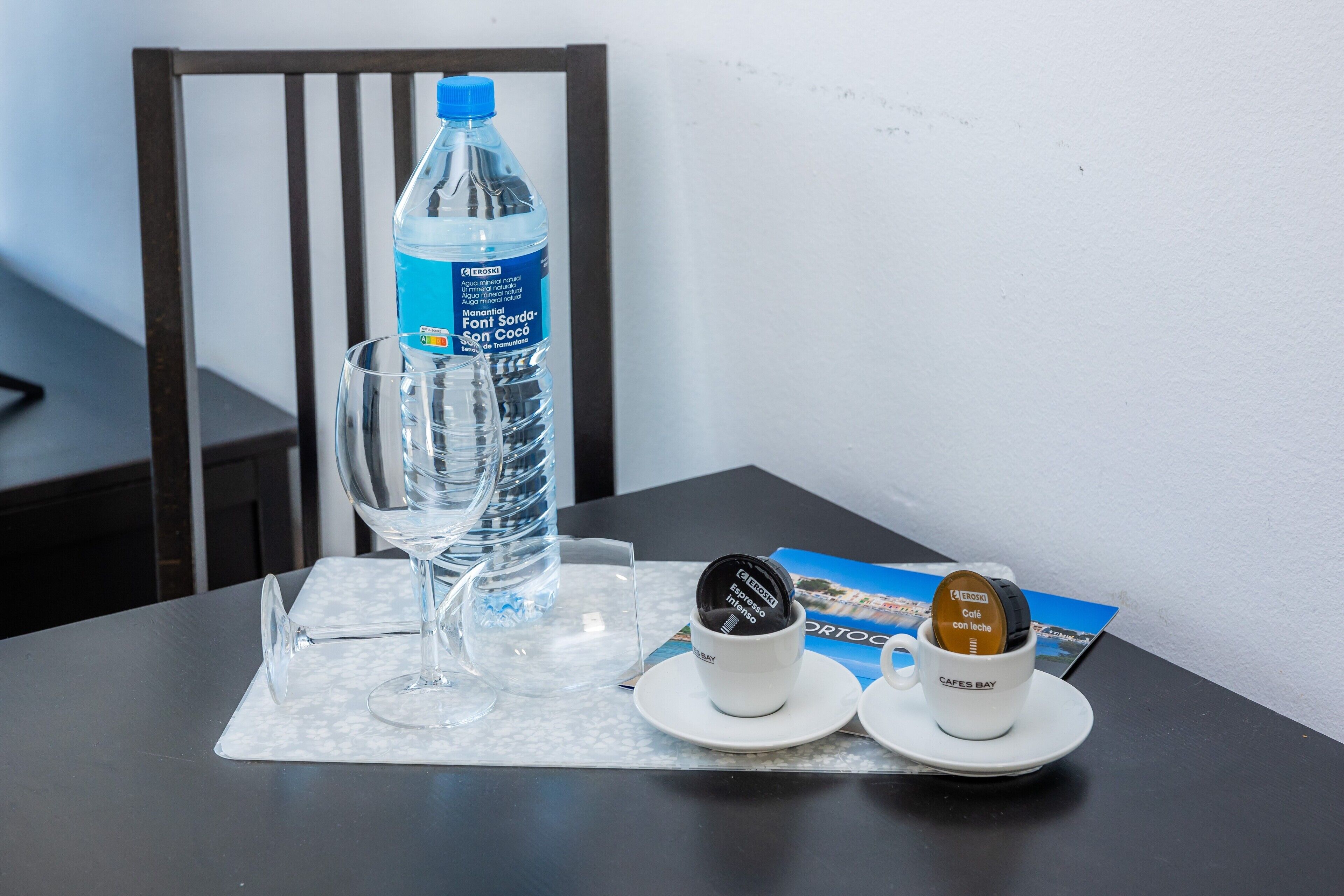 Une table avec une bouteille d’eau, deux tasses à café et un verre.