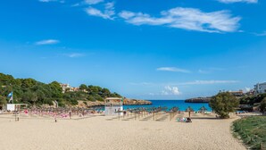 Une plage avec des parasols, des chaises longues et un poste de surveillance pour les sauveteurs.