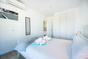 A hotel room with a bed, a wardrobe, a mirror, and an air conditioning unit.