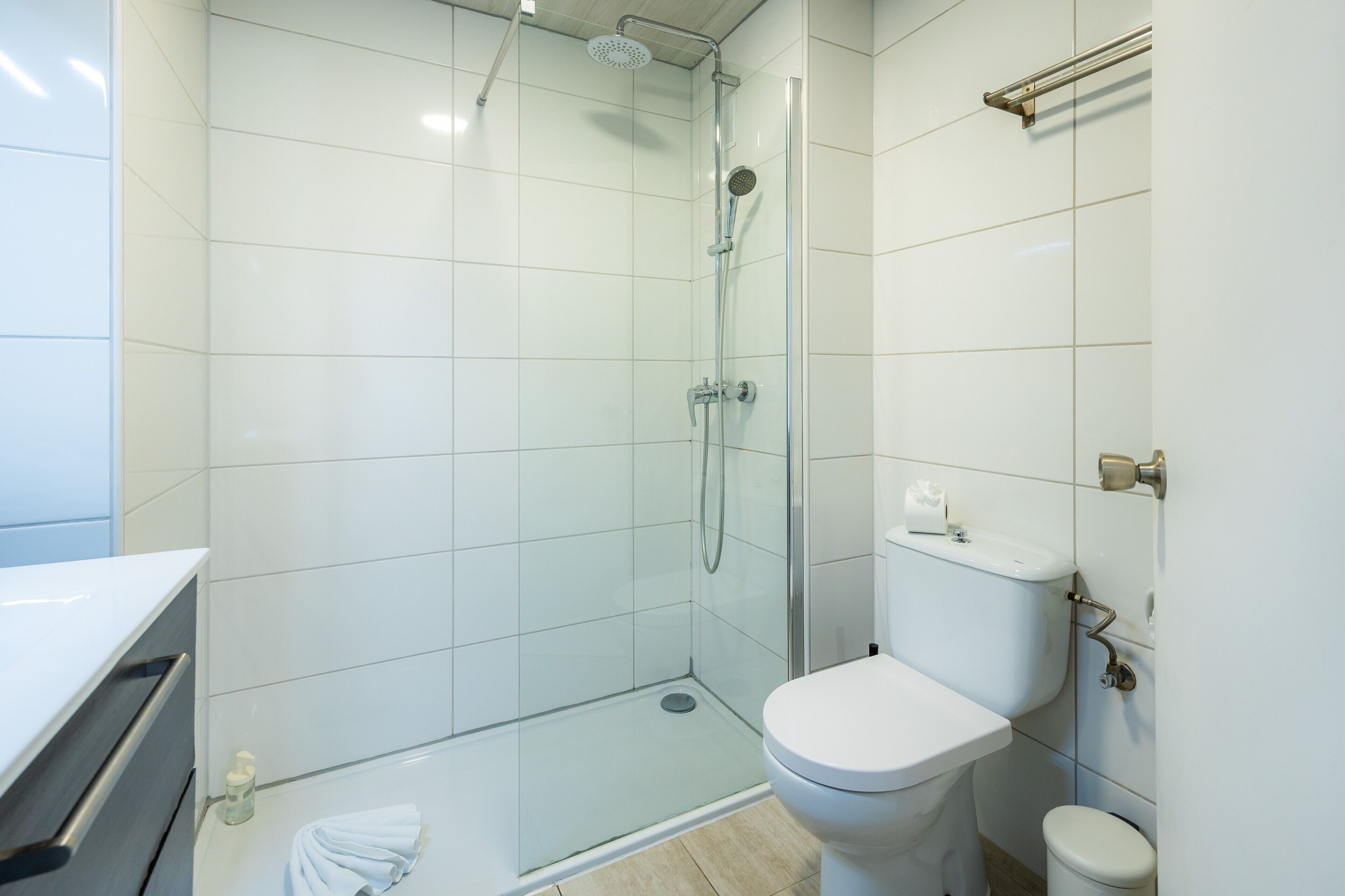 Un baño moderno con ducha envuelta en vidrio, inodoro blanco y lavamanos blanco.