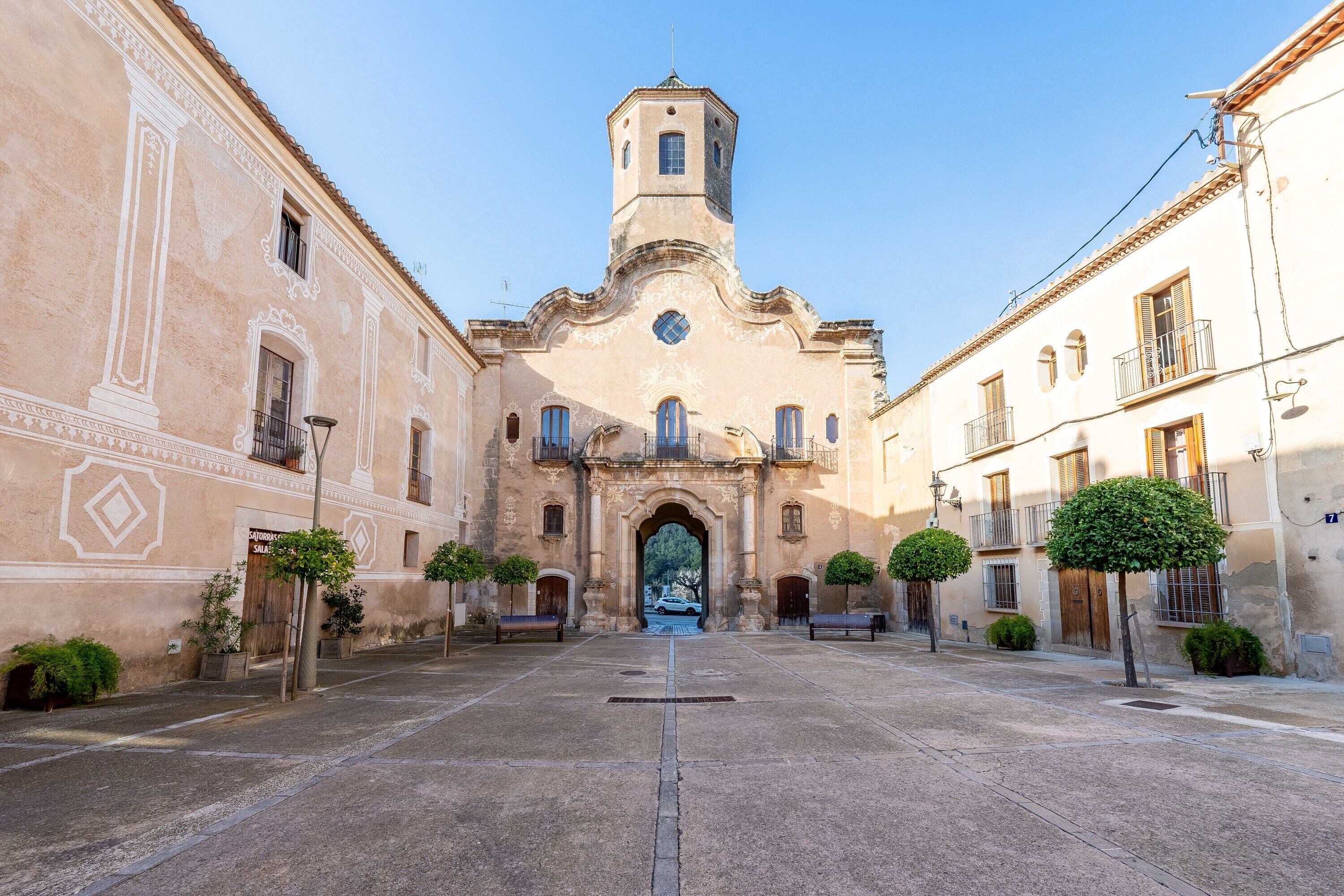 Une cour avec une église, des bancs et des arbres.
