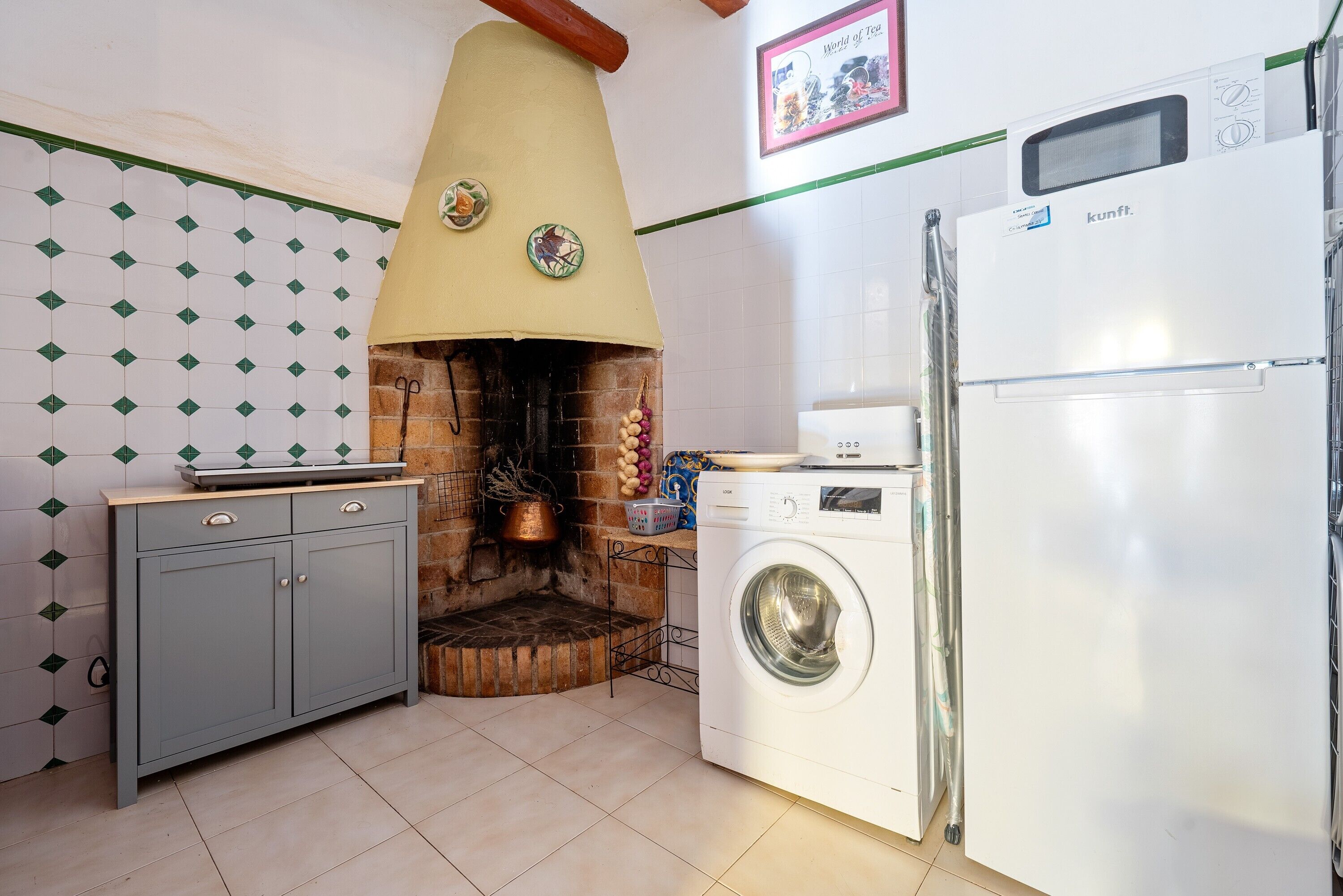 A kitchen with a brick oven, a washing machine, and a refrigerator.