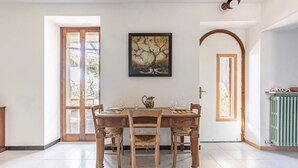 A dining area with a wooden table, chairs, and a painting on the wall. - GuestHost - Enchanting and spacious villa on two levels, which in 125 sqm accommodates up to 5 guests with great comfort, being equipped with every type of comfort: two bedrooms and three bathrooms, Jacuzzi tub, large private garden with barbecue and piz (Castel Rigone)