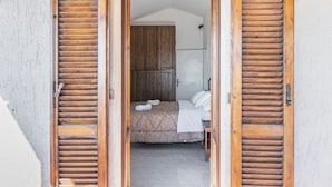 A bedroom with a bed, wooden shutters, a wardrobe, and a tiled floor. - GuestHost - Enchanting and spacious villa on two levels, which in 125 sqm accommodates up to 5 guests with great comfort, being equipped with every type of comfort: two bedrooms and three bathrooms, Jacuzzi tub, large private garden with barbecue and piz (Castel Rigone)