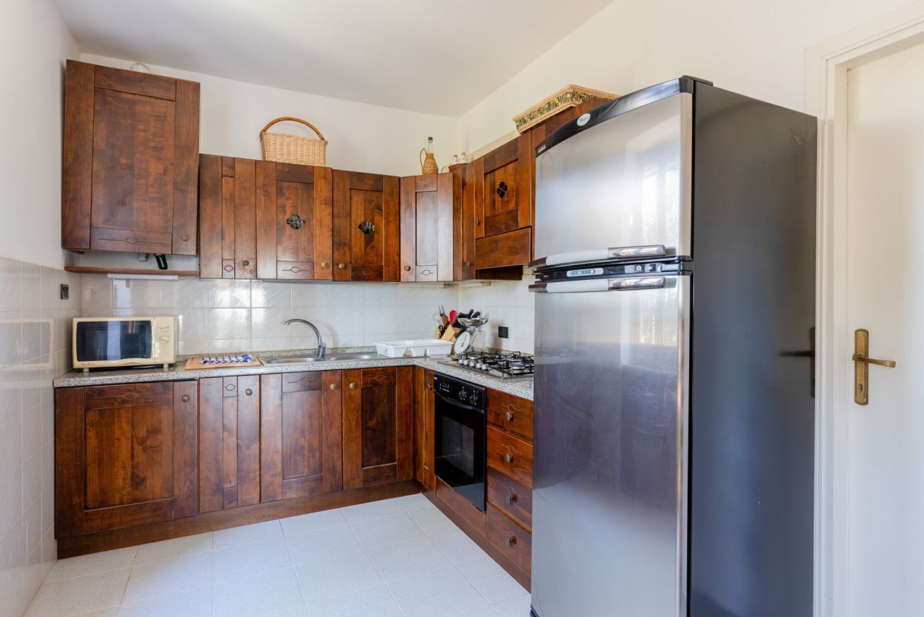 Una cocina con armarios de madera, un refrigerador de acero inoxidable, un microondas, una estufa a gas y un lavavajillas.