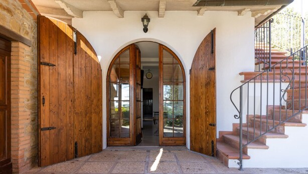 A stone-floored entrance with wooden doors and a staircase. - GuestHost - Enchanting and spacious villa on two levels, which in 125 sqm accommodates up to 5 guests with great comfort, being equipped with every type of comfort: two bedrooms and three bathrooms, Jacuzzi tub, large private garden with barbecue and piz (Castel Rigone)
