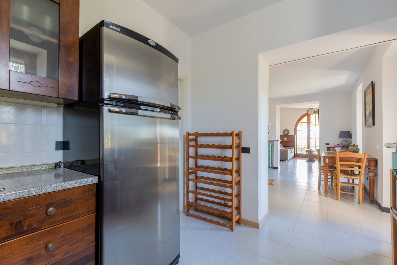 A kitchen with a stainless steel refrigerator, wooden cabinets, and a tiled backsplash.