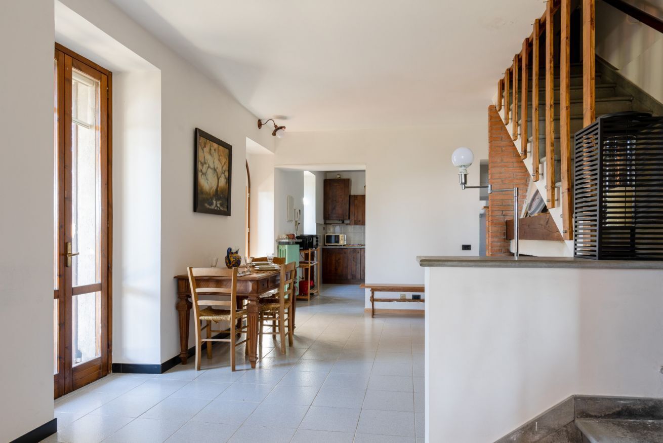 A spacious kitchen with modern appliances, a dining area with wooden furniture, and a staircase with exposed wooden beams.