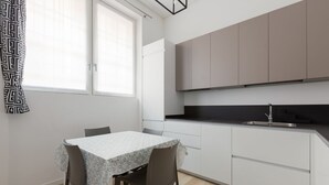 Cuina moderna amb armaris blancs, tauleig negre i finestra amb cortina.