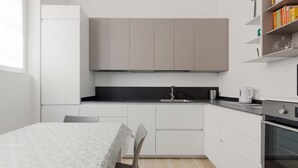 Una cuina moderna amb armaris blancs, taulell negre i una taula de dinar amb cadires.
