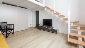 A modern living space with a staircase, a flat-screen TV, and a minimalist design.