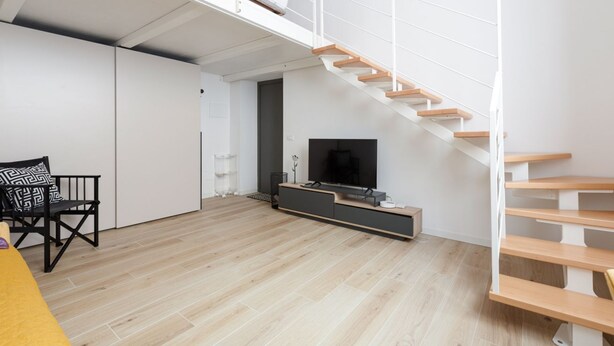 Un espai de viure modern amb una escala, un televisió de pantalla plana i un disseny minimalista.