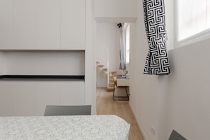 A modern bedroom with a bed, a desk, and a staircase leading to an upper level. - GuestHost - MM Jerusalem Subway Loft x4 (Milano)