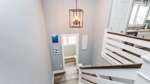 A staircase with white railings and a wooden finish, leading to a kitchen area with white cabinets and a stainless steel sink. - Soundside, ELEV, Priv Pool, Hot Tub, Community Amenities- MS853, Resting Beach Place (Corolla)