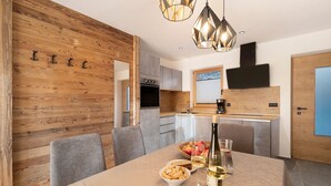 A modern kitchen with wooden accents, a dining table with food and drinks, and a TV mounted on the wall.