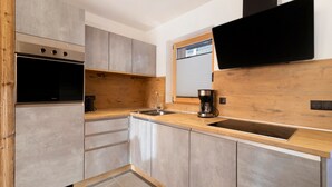 A modern kitchen with a built-in oven, a coffee maker, and a flat-screen TV mounted on the wall.