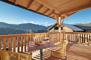 A wooden deck with a table and chairs, a bottle of wine, and a basket of bread. - Apartment 'Karspitz' with Mountain View, Private Terrace and Wi-Fi (Rodengo)