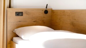 A wooden bed with a headboard, a bedside lamp, and a power outlet.