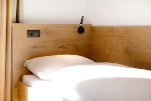 A wooden bed with a headboard, a bedside lamp, and a power outlet.
