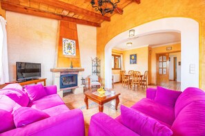 Ein Wohnzimmer mit Kamin, Fernseher und leuchtend rosa Sofas.