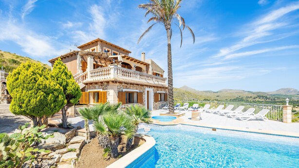 Eine zweistöckige Villa mit Swimmingpool, einer Palme und Blick auf die Hügel.