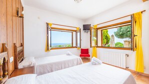 Ein Zimmer mit zwei Betten, einer Holzwand, einem Fenster mit Blick und einem roten Sessel.