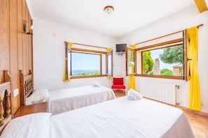 Une chambre avec deux lits, un mur en bois, une fenêtre donnant sur un beau paysage et une chaise rouge.