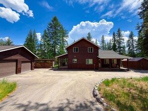 Una baita di legno a due piani con un garage, immersa tra gli alberi.