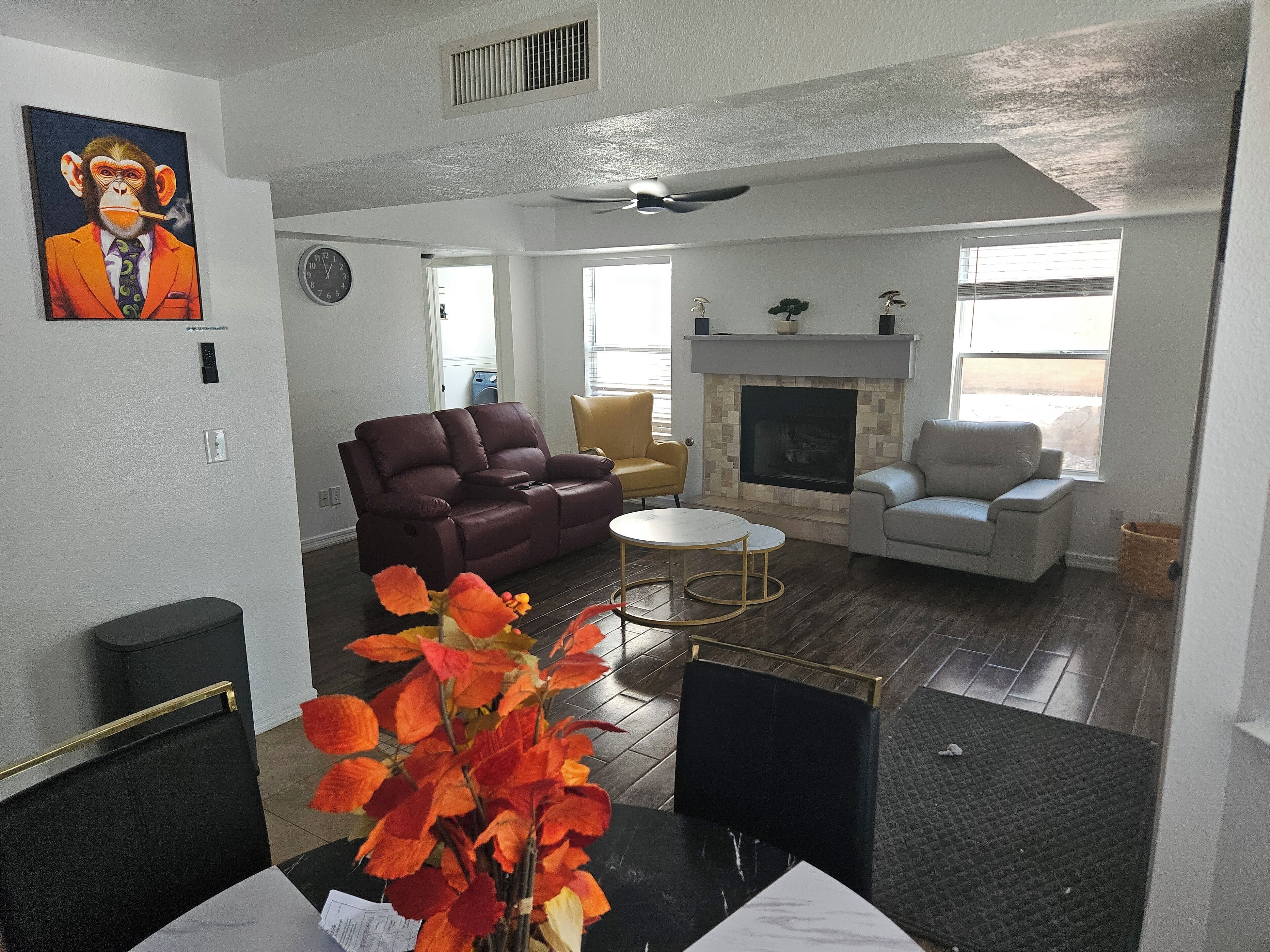 A living room with a fireplace, a sofa, a coffee table, and a dining area with a vase of flowers.