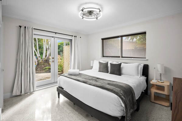 A bedroom with a bed, a window, a bedside table, and a ceiling fan.
