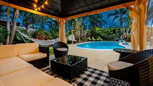 Un’area esterna coperta con piscina, poltroncine relax e un tavolo.