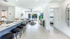 Eine moderne Küche mit Bar, Essbereich und Blick auf einen Swimmingpool.