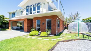 A modern two-story house with a garage, a balcony, and a greenhouse. - Close to Beach | Spacious | Outdoor Living - KK00379 (Kaikoura)