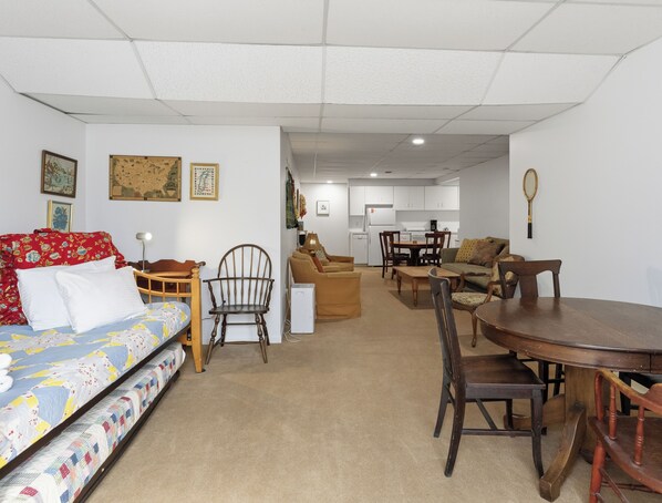 A compact living space with a bed, sofa, dining table, chairs, and a kitchenette in the background.
