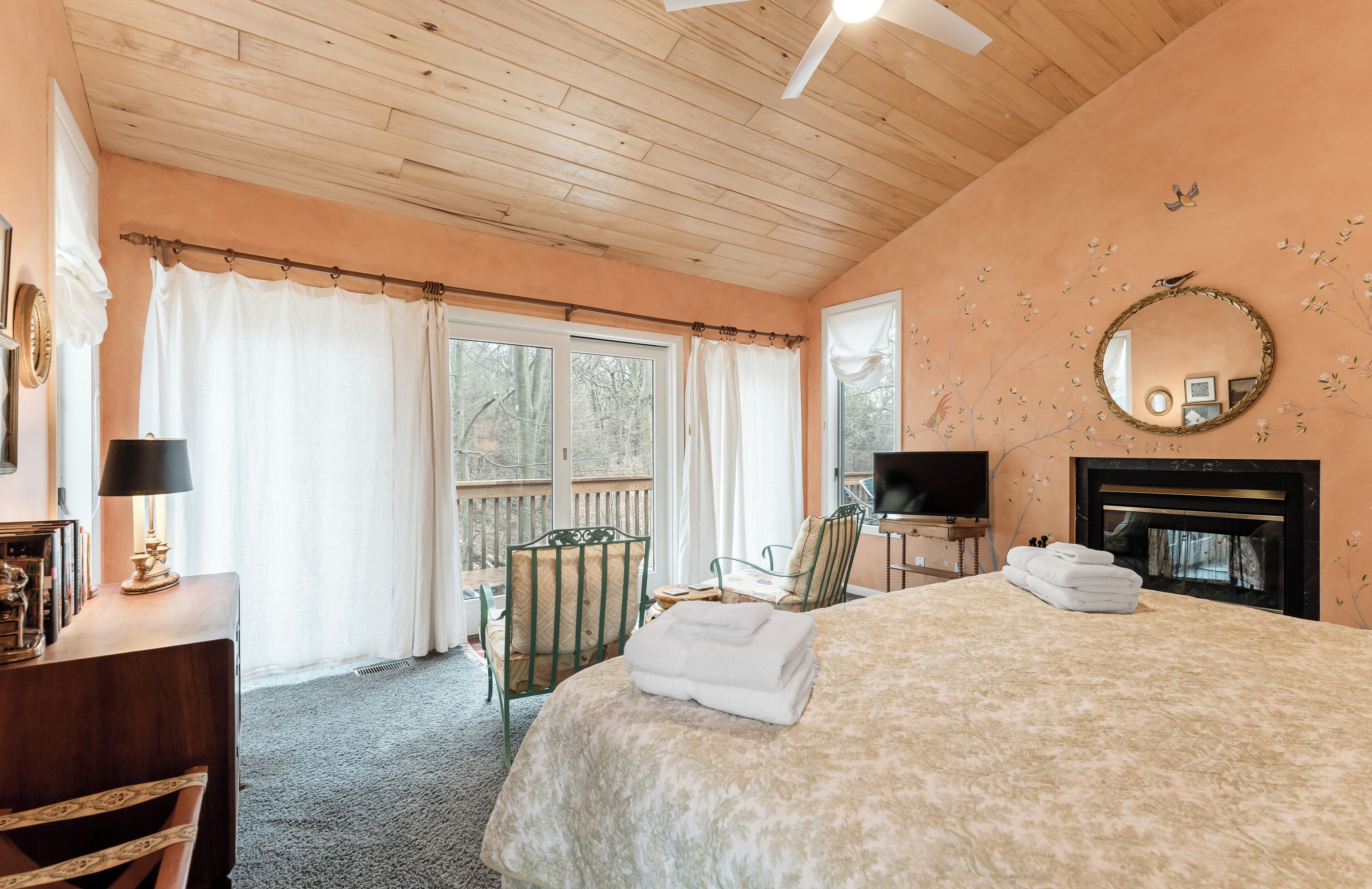 Une chambre à coucher comprenant un lit, une télévision, une cheminée et un balcon avec des rideaux.