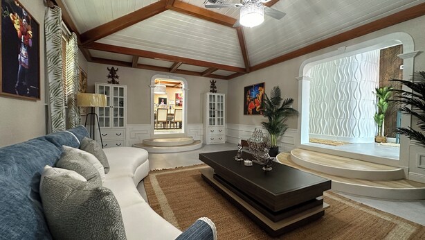A spacious living room with a large sectional sofa, a dark coffee table, and a view of the dining area through an arched doorway. - Island Chic Vacation Manor in the tranquil community of Coral Harbour, Bahamas (Nassau)