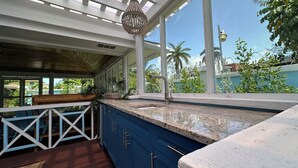 A kitchen with blue cabinets, a granite countertop, and a hanging light fixture. - Island Chic Vacation Manor in the tranquil community of Coral Harbour, Bahamas (Nassau)