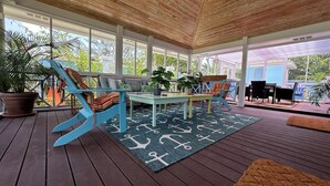 A covered outdoor area with wooden flooring, a table, chairs, and potted plants. - Island Chic Vacation Manor in the tranquil community of Coral Harbour, Bahamas (Nassau)