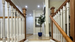 A staircase with white balusters and wooden handrails, leading to a landing with a potted plant. - Island Chic Vacation Manor in the tranquil community of Coral Harbour, Bahamas (Nassau)