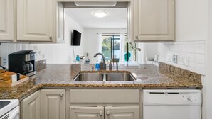 Eine moderne Küche mit Granit-Arbeitsplatten, Edelstahlgeräten und weißen Schränken.