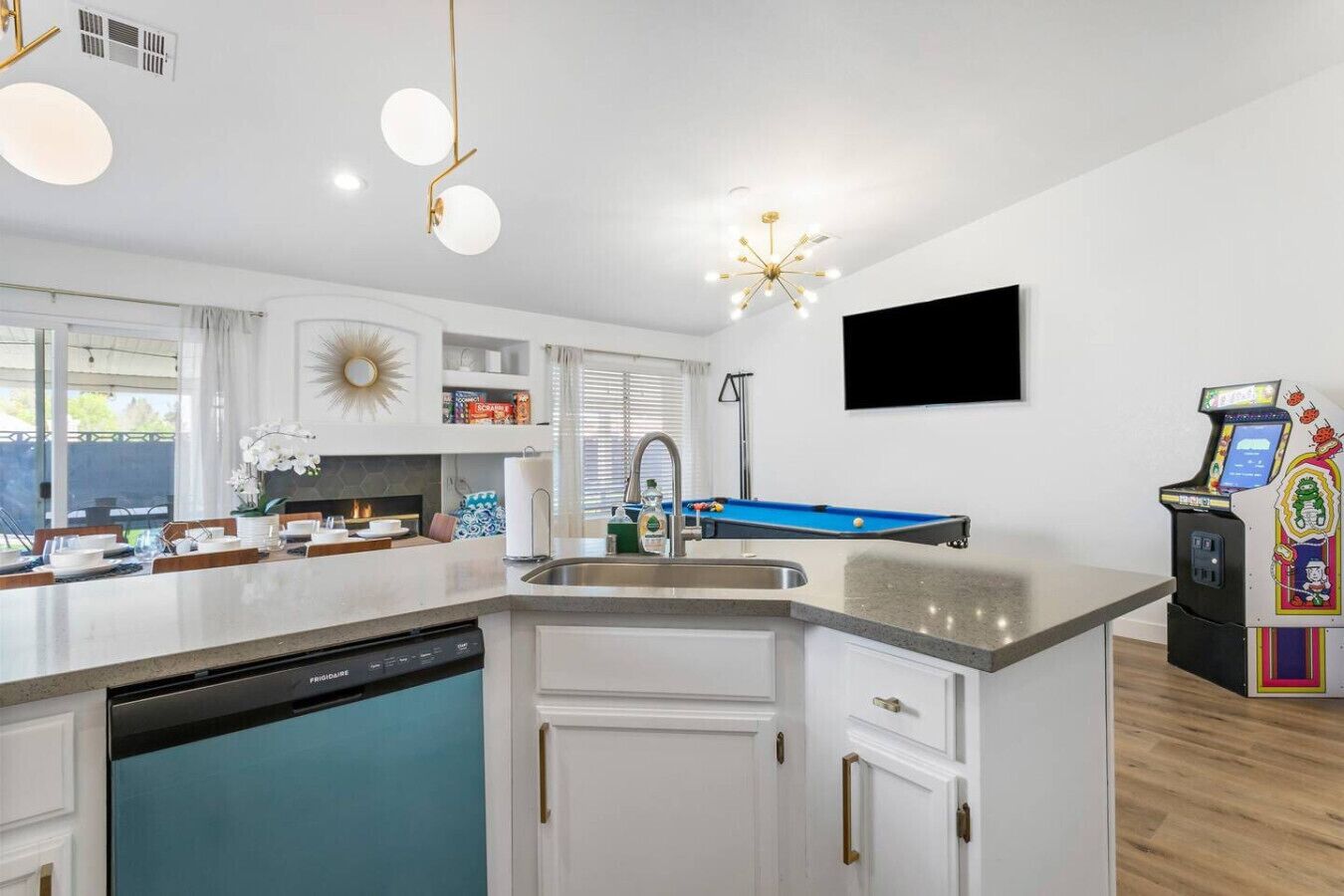 Een moderne keuken met een vaatwasser, een blauwe pooltafel en een flatscreen televisie aan de muur.