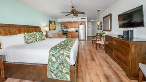 A hotel room with a bed, a desk, a chair, a television, and a kitchenette. - Royal Kahana Maui 719 Ocean View Studio (Lahaina)