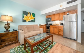 A living room with a sofa, coffee table, and a painting of a flower.