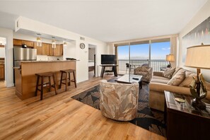A modern apartment with a kitchen, living area, and balcony with a view.