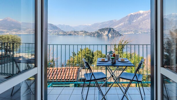 A balcony with a table and chairs overlooking a lake with mountains in the background. - Apartment Lella by Interhome (Varenna)
